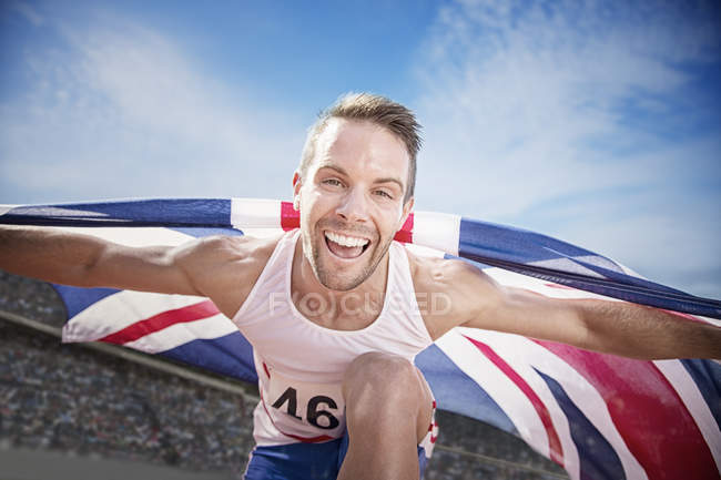 Track and field athlete cheering with British flag — Stock Photo