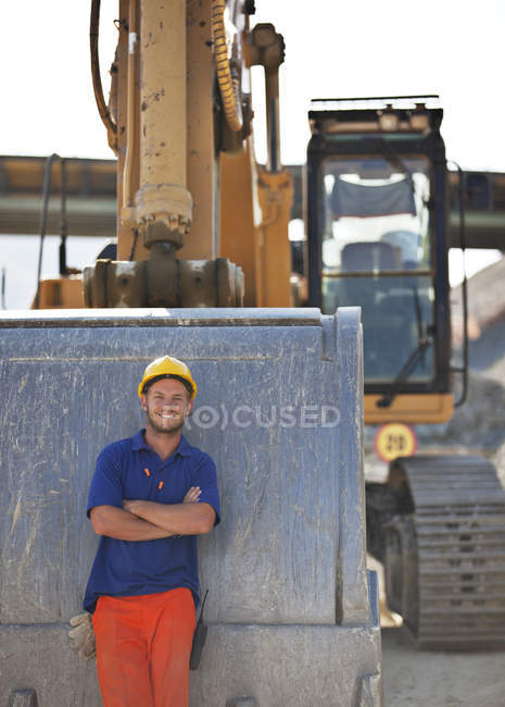 Arbeiter steht neben Bagger auf Baustelle — Stockfoto