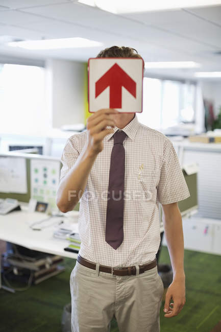 Бизнесмен держит табличку со стрелкой в современном офисе — стоковое фото
