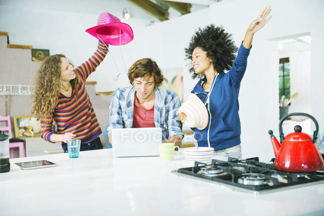 Jóvenes amigos felices jugando en la cocina - foto de stock