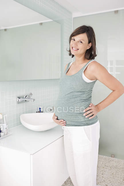 Беременная женщина, стоящая в ванной — стоковое фото