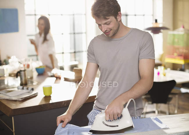 Мужчина гладильная рубашка на кухне — стоковое фото