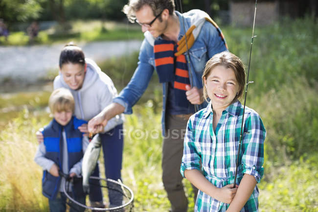 Family admiring fishing catch outdoors — Stock Photo