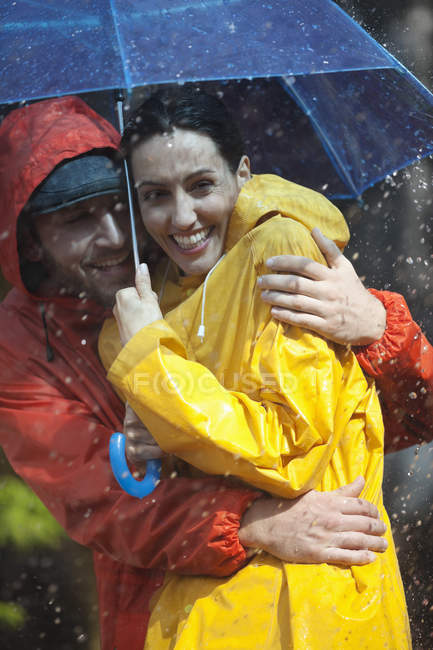Felice coppia che abbraccia sotto l'ombrello sotto la pioggia — Foto stock