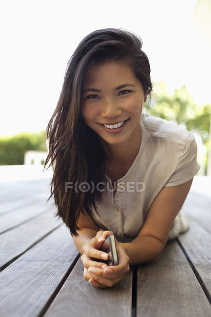 Young attractive Woman using cell phone on wooden deck — Stock Photo