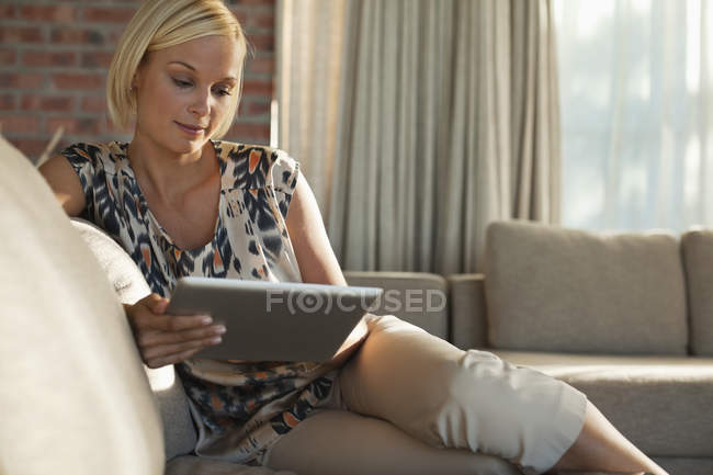 Mulher usando computador tablet no sofá — Fotografia de Stock