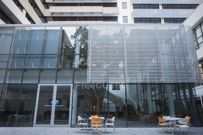 Обеденные столы возле стеклянного офисного здания — стоковое фото