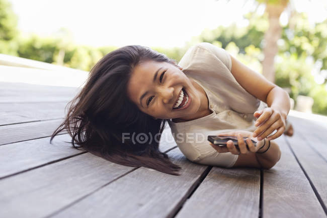 Mulher usando telefone celular no deck de madeira — Fotografia de Stock