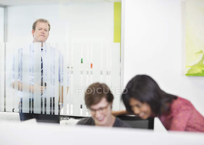 Businessman eavesdropping on colleagues at modern office — Stock Photo