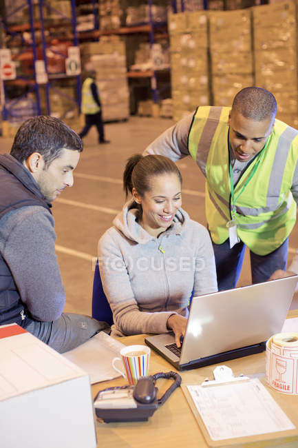 Workers using laptop in warehouse — Stock Photo
