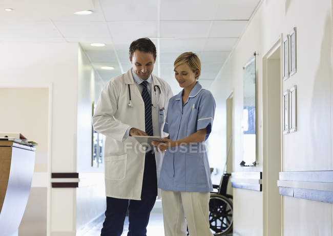 Лікар і медсестра використовують планшетний комп'ютер в лікарняному коридорі — стокове фото