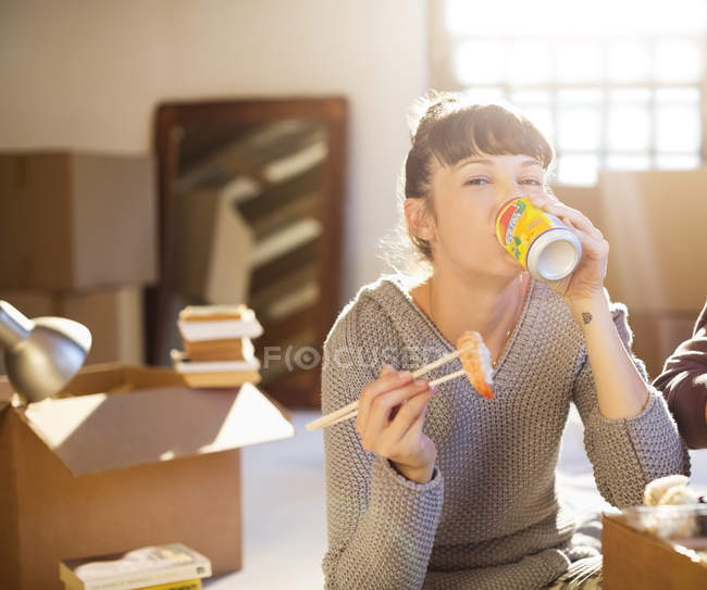 Mulher bebendo refrigerante e comendo sushi em nova casa — Fotografia de Stock