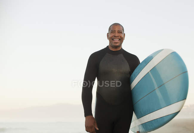 Älterer Surfer trägt Brett am Strand — Stockfoto