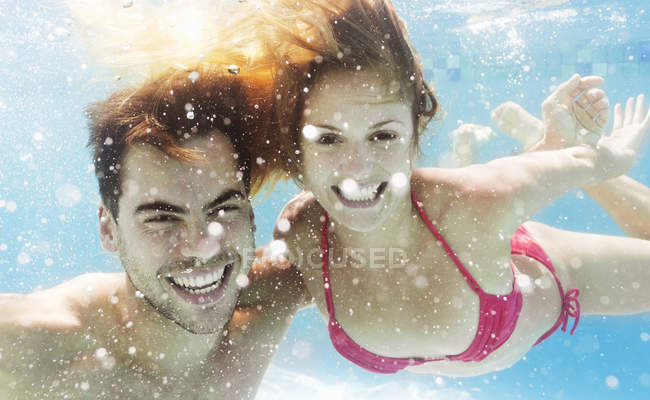 Felice coppia caucasica nuotare in piscina — Foto stock