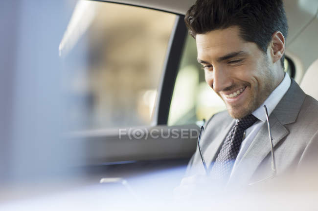 Homme d'affaires utilisant un téléphone portable dans le siège arrière de la voiture — Photo de stock