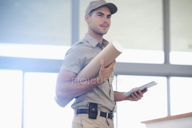 Delivery boy carrying package at modern office — Stock Photo