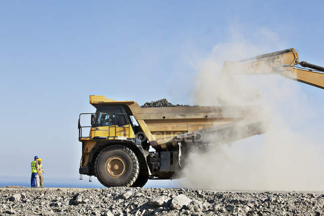 Lavoratori che supervisionano scavatori e camion in cava — Foto stock