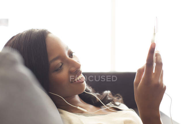 Молода приваблива жінка слухає навушники на дивані — стокове фото