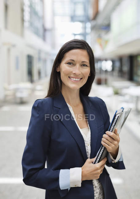 Donna d'affari che trasporta cartelle in ufficio moderno — Foto stock