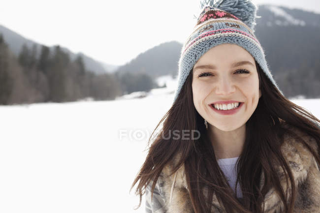 Close up portrait of happy woman wearing knit hat in snowy field — Stock Photo