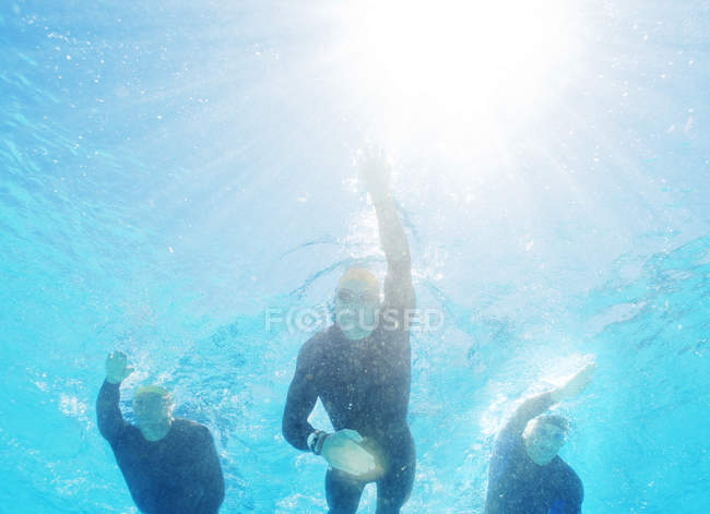 Уверенные и сильные триатлонисты в гидрокостюмах под водой — стоковое фото