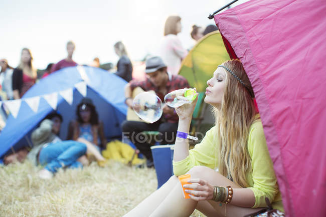 Woman blowing bubbles from tent at music festival — Stock Photo