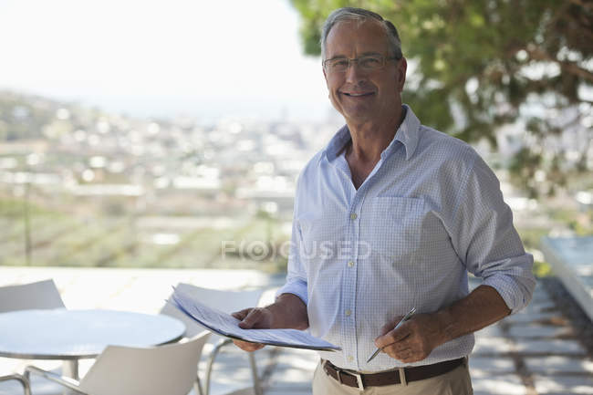 Hombre mayor leyendo papeles al aire libre - foto de stock