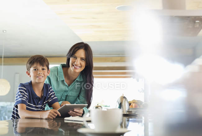 Mãe e filho usando tablet computador na cozinha — Fotografia de Stock