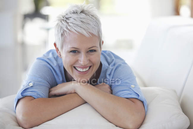 Frau stützt Kinn in Händen auf Sofa — Stockfoto