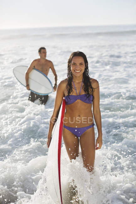 Portrait of smiling woman with surfboard in ocean — Stock Photo