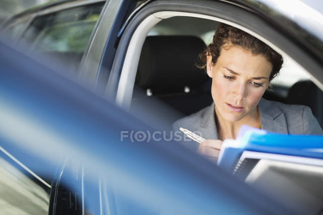 Attractive adult businesswoman working in car — Stock Photo