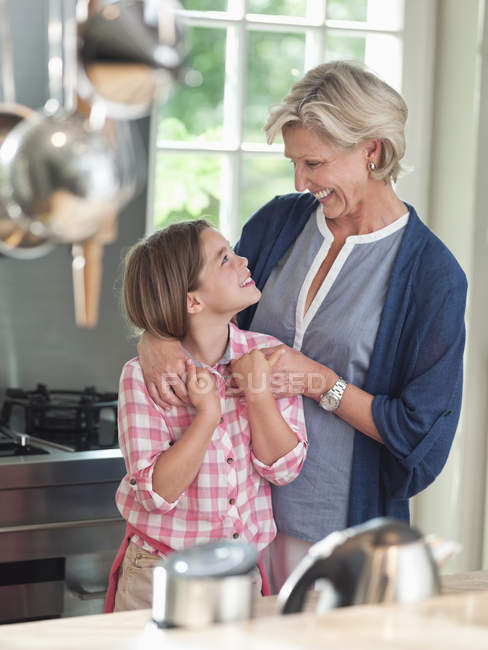 Женщина и внучка улыбаются на кухне — стоковое фото