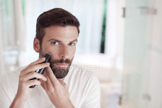 Чоловік обрізає бороду у дзеркалі ванної кімнати — стокове фото
