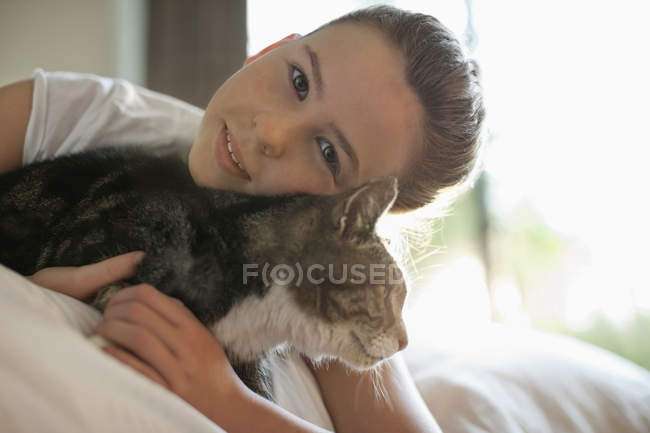 Девушка ласкает кошку на кровати, вид крупным планом — стоковое фото