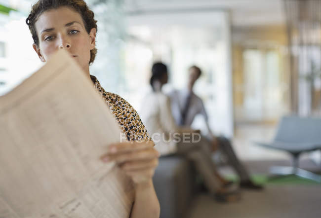 Geschäftsfrau liest Zeitung im modernen Büro — Stockfoto