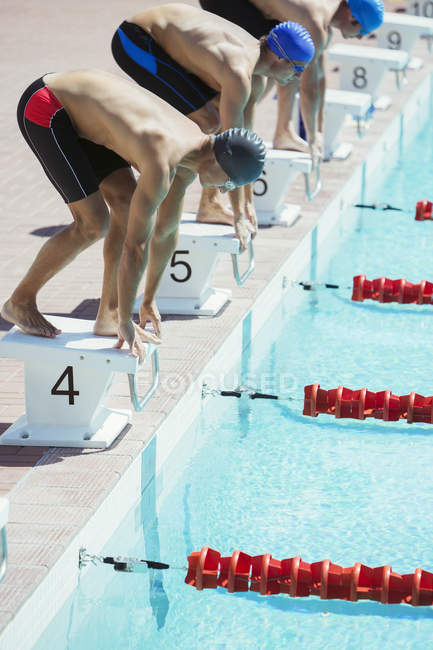 Swimmers poised at starting blocks — Stock Photo