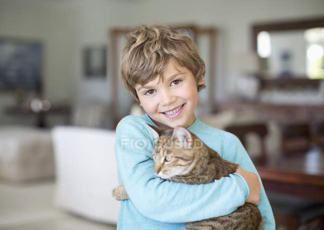 Caucasiano menino abraçando gato na sala de estar — Fotografia de Stock