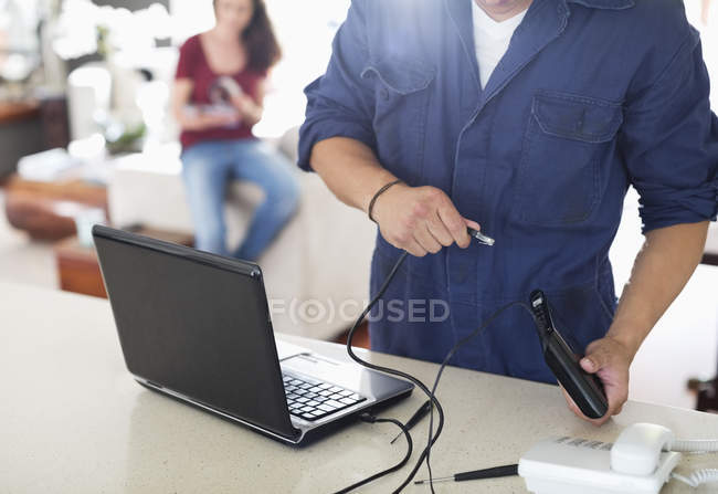 Hábil electricista caucásico usando el ordenador portátil en casa - foto de stock