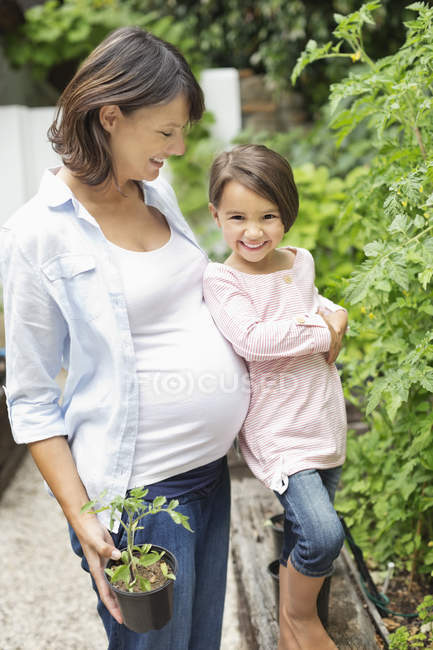 Mädchen und schwangere Mutter bei der gemeinsamen Gartenarbeit — Stockfoto