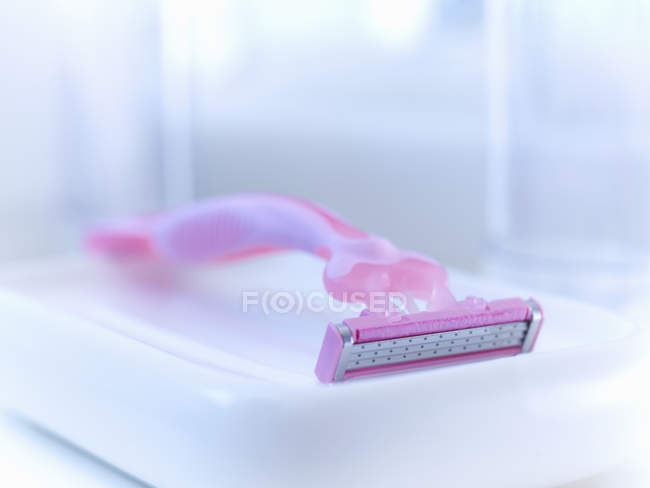 Primer plano de maquinilla de afeitar rosa en baño - foto de stock