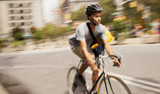 Hombre en casco a caballo bicicleta en la calle de la ciudad - foto de stock