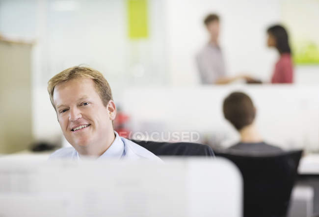Empresario sonriendo en el escritorio en la oficina moderna - foto de stock