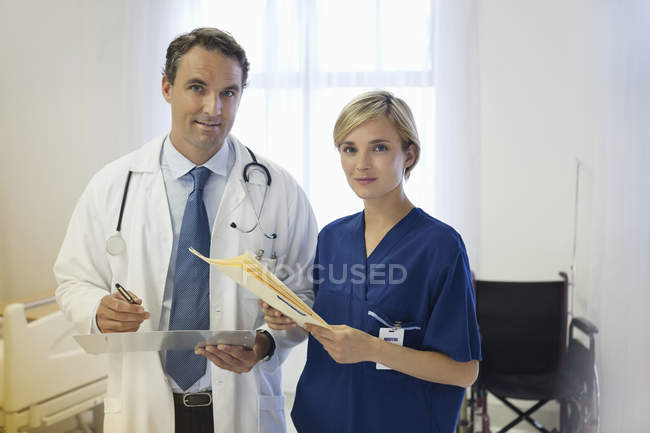 Médico y enfermera hablando en la habitación del hospital - foto de stock