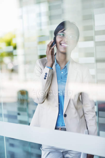 Mujer de negocios hablando por teléfono celular en la oficina moderna - foto de stock
