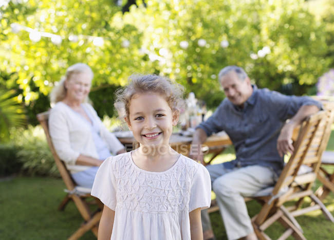 Girl smiling in backyard with grandparents — Stock Photo