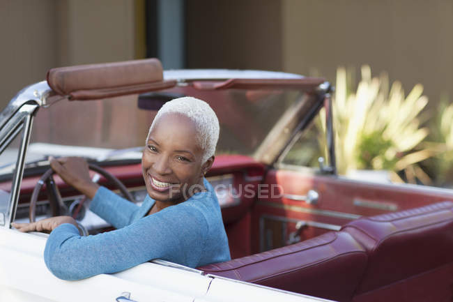 Улыбающаяся пожилая женщина за рулем кабриолета — стоковое фото