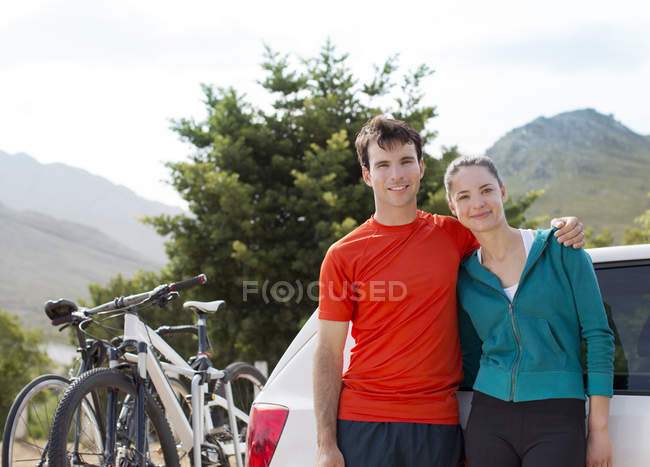 Couple smiling by car in rural landscape — Stock Photo