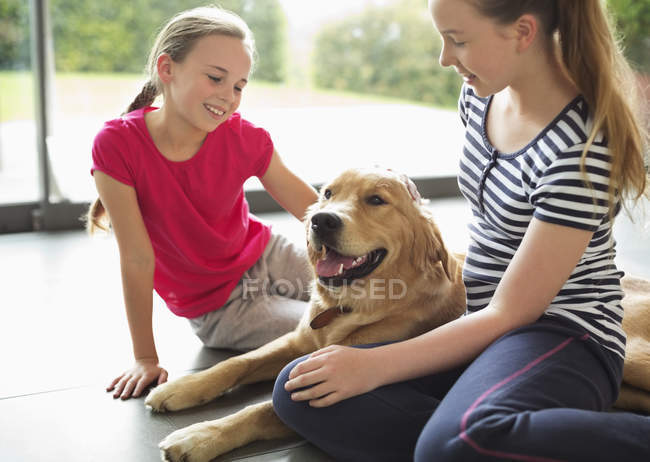 Meninas relaxando com o cão na sala de estar na casa moderna — Fotografia de Stock