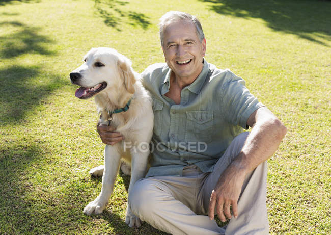 Older man hugging dog in backyard — Stock Photo