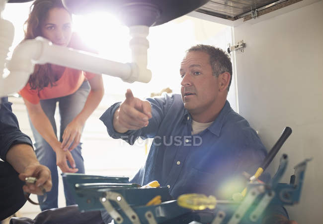 Skillful caucasian plumbers working on pipes under sink — Stock Photo